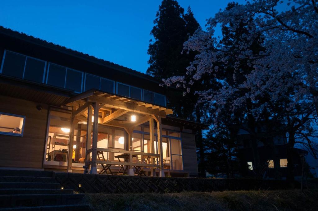 una casa con un porche iluminado por la noche en Shirakawago Guest House Kei, en Shirakawa