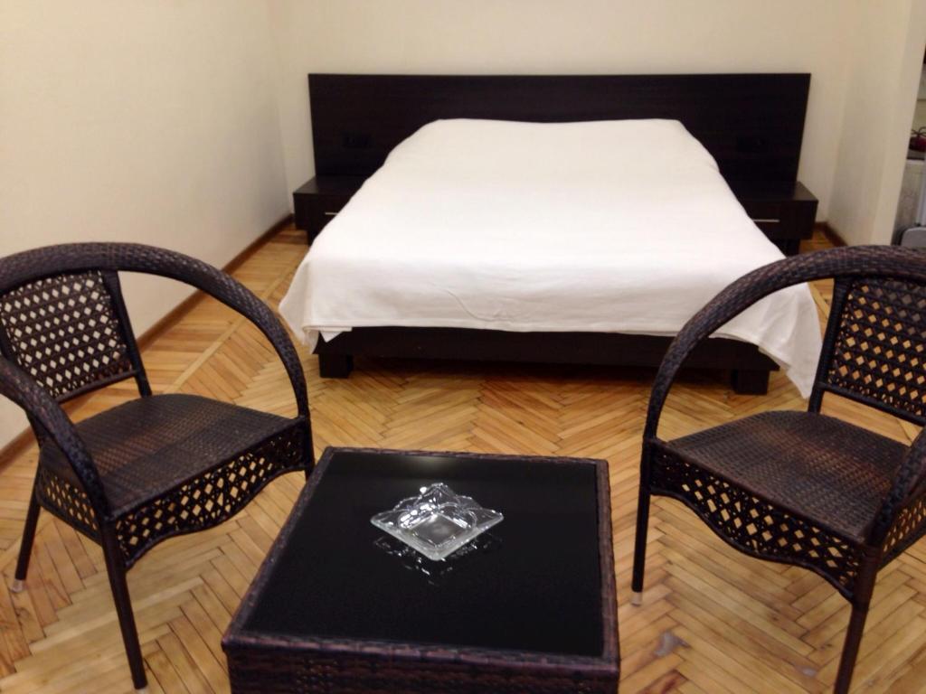 een slaapkamer met een bed en 2 stoelen en een tafel bij Yerevan Center Studio Apartment in Jerevan