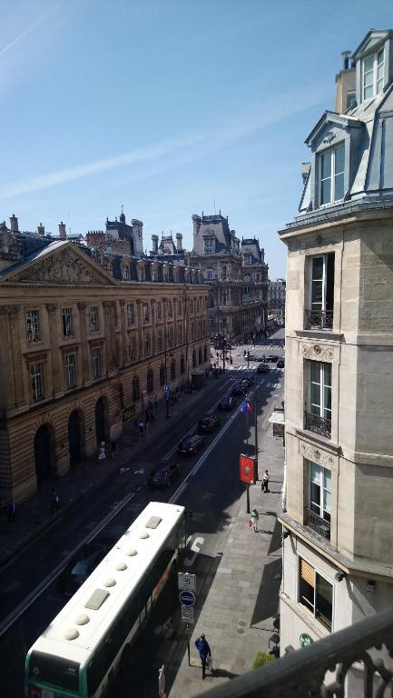 um autocarro a descer uma rua da cidade com edifícios em Hotel Rivoli em Paris