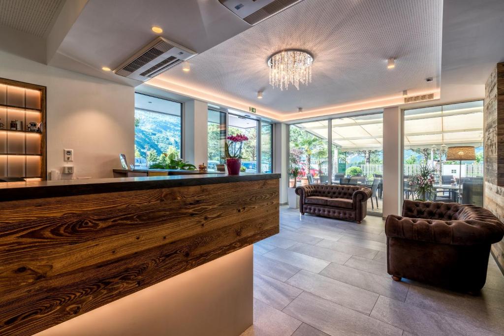 a lobby with a wooden bar with leather chairs and windows at Residence Martinelli in Laives