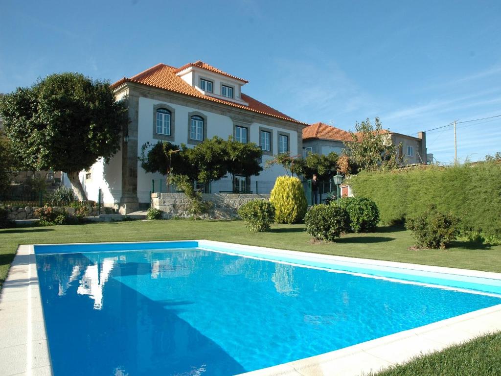 a blue swimming pool in front of a house at Quinta da Casa Grande Pinheiro in Santa Marinha do Zêzere