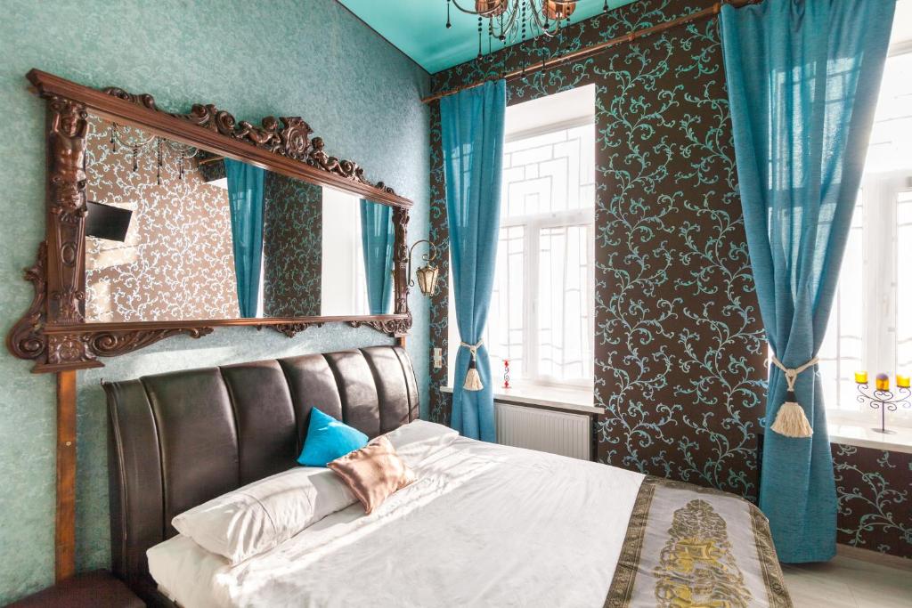 Schlafzimmer mit einem Bett mit einem Spiegel und blauen Wänden in der Unterkunft Austrian Apartments in Lwiw