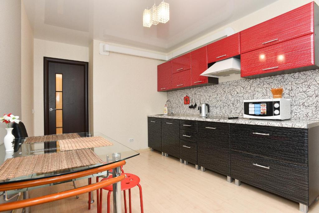 a kitchen with red cabinets and a table with chairs at СелимВсех на Куйбышева in Yekaterinburg