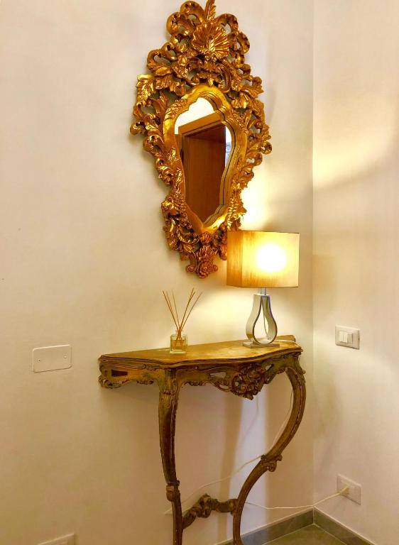 a mirror on a wall with a table with a lamp at Hotel Ariel Silva in Venice