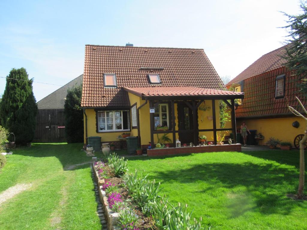 a yellow house with a red roof on a yard at Ferienwohnung Sommer in Friedrichsbrunn