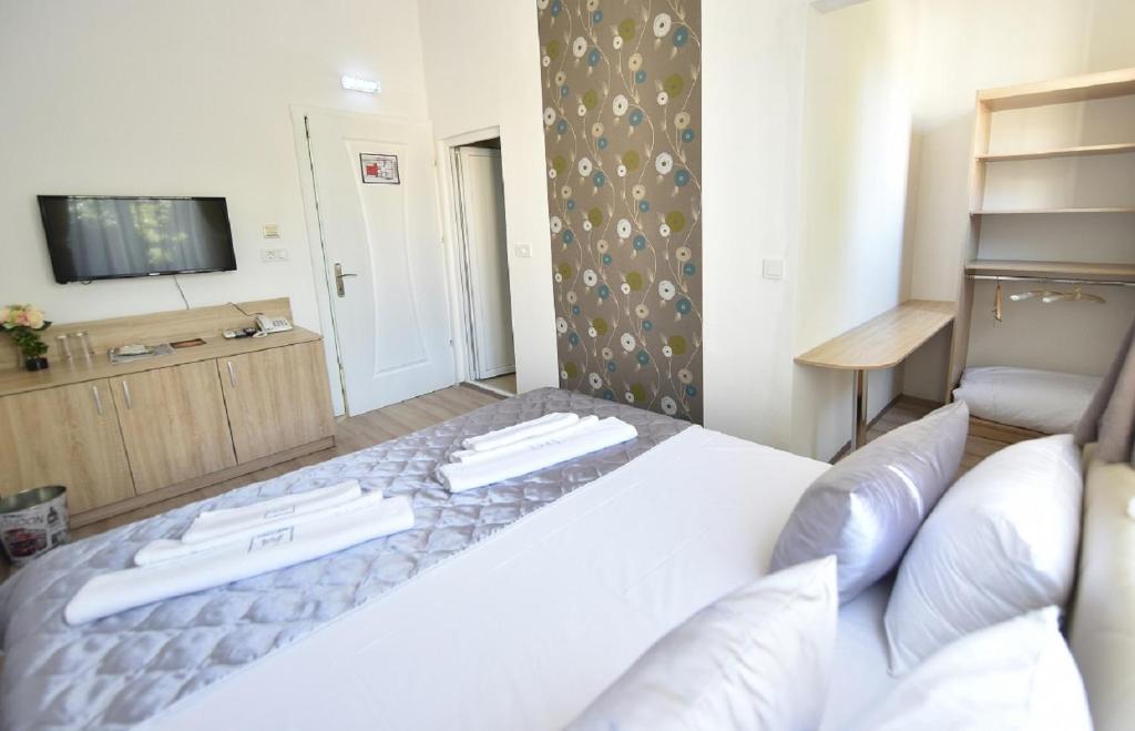 - une chambre avec un lit blanc et une télévision dans l'établissement Villa Nina Hotel & Lounge bar, à Skopje