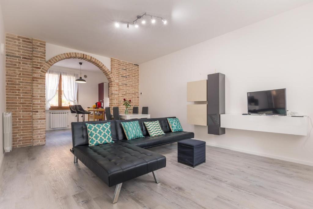 sala de estar con sofá negro y TV en CaMagnolia Apartment, en Montegrotto Terme