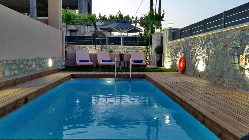 una piscina en un patio trasero con una terraza de madera y sillas en Sunrise Residence, en Koxaré