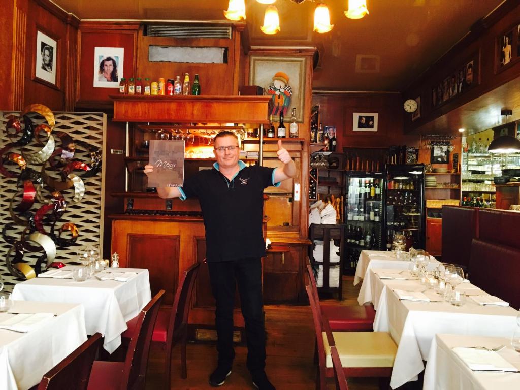 Een man in een restaurant die een bord omhoog houdt. bij Boutique Hotel Couleurs Suds in Cannes