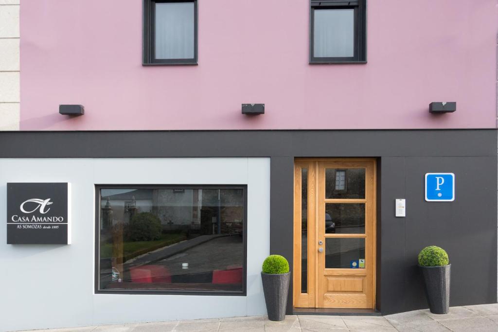 um edifício cor-de-rosa com uma porta e duas plantas em Casa Amando em Somozas