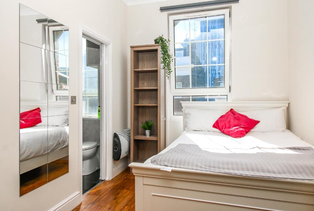 um quarto com uma cama com almofadas vermelhas em Private en-suite Room @ Liverpool street, Brick Ln em Londres