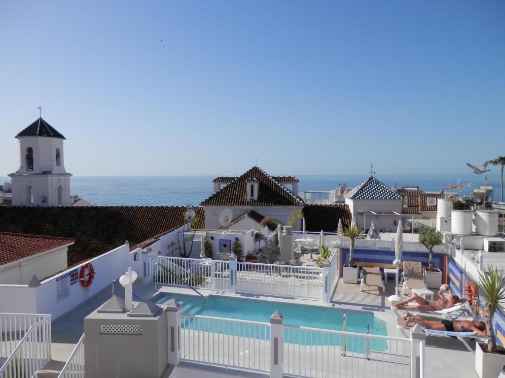 a beach with a pool and a house at Hotel Puerta del Mar in Nerja