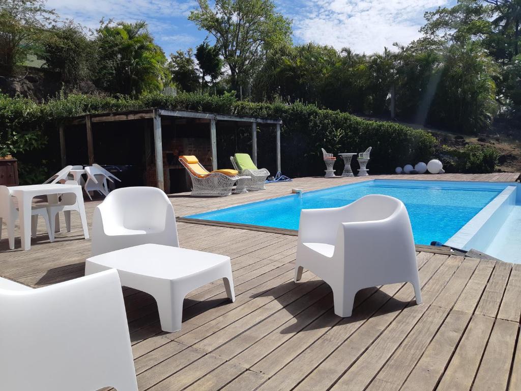 a patio with white chairs and a swimming pool at Domaine Choco Vanille in Deshaies