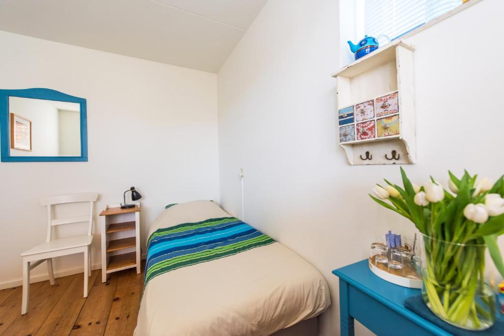 ein kleines Schlafzimmer mit einem Bett und einem blauen Tisch in der Unterkunft de Vloedlijn in Callantsoog