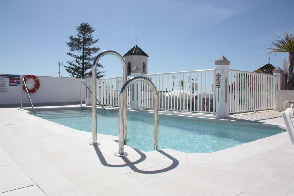 a swimming pool with metal hand rails next to it at Hotel Puerta del Mar - Adults Recommended in Nerja