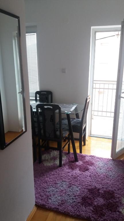 a dining room table with chairs and a purple rug at Apartments Milijana in Soko Banja