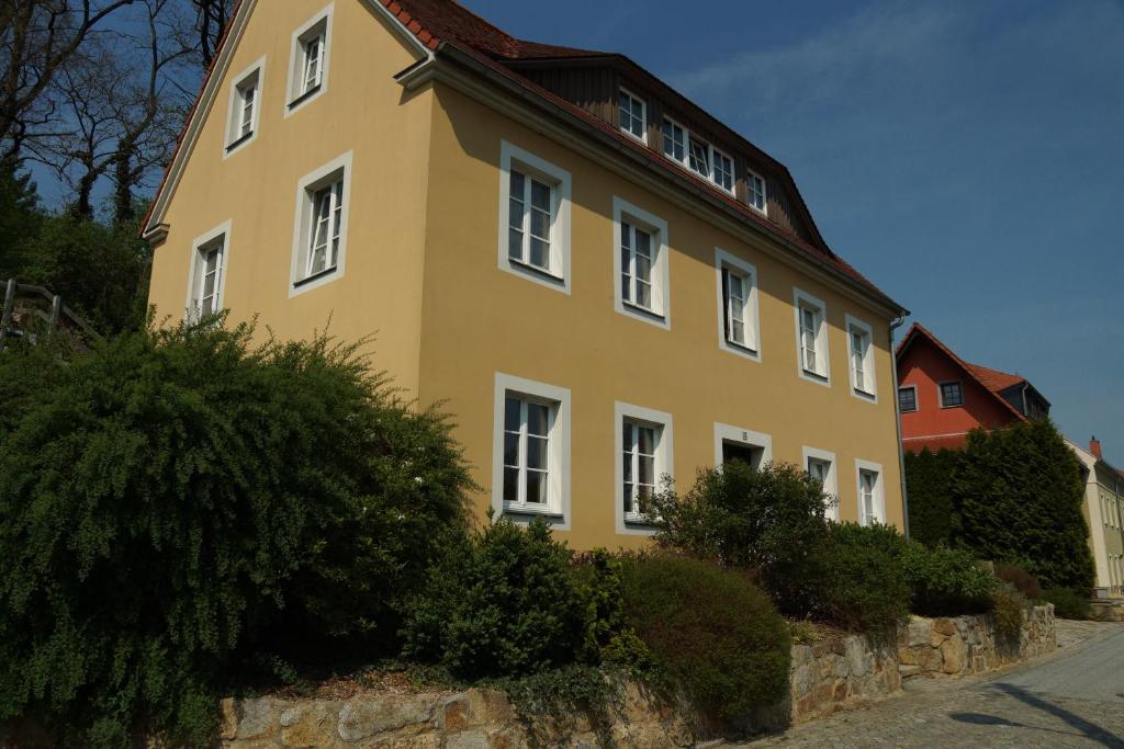 a yellow building with white windows on a street at Ferienwohnung am Spreeradweg in Bautzen in Bautzen