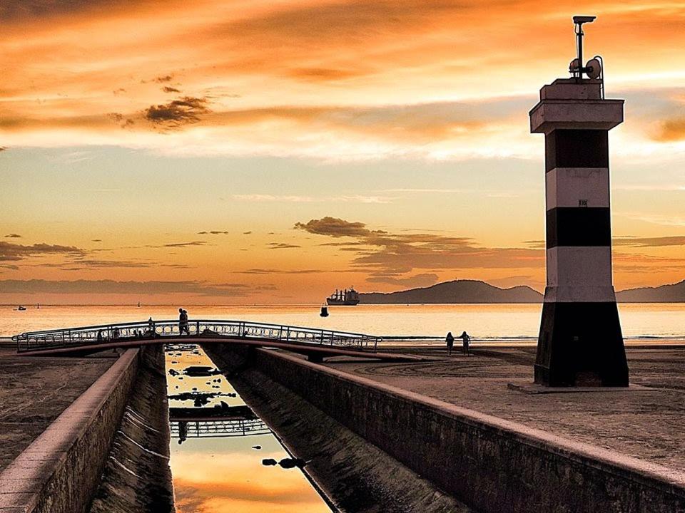 a lighthouse on a pier next to the ocean at Sala-living/ 1 quadra da praia in Santos