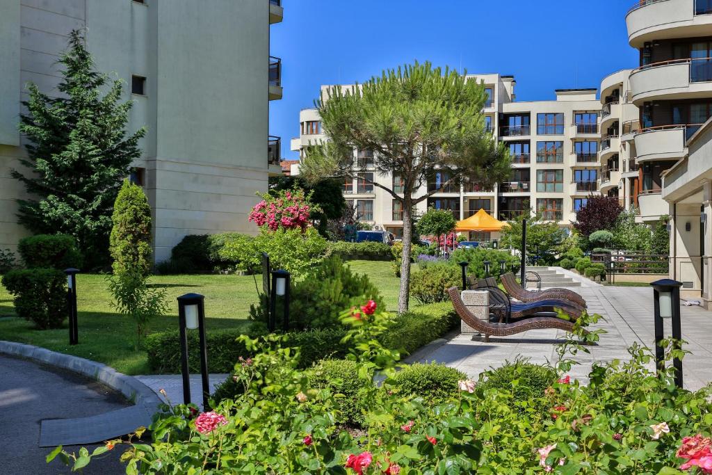 un parque con bancos y flores frente a un edificio en Al Rial Beach Apartments en Shkorpilovtsi