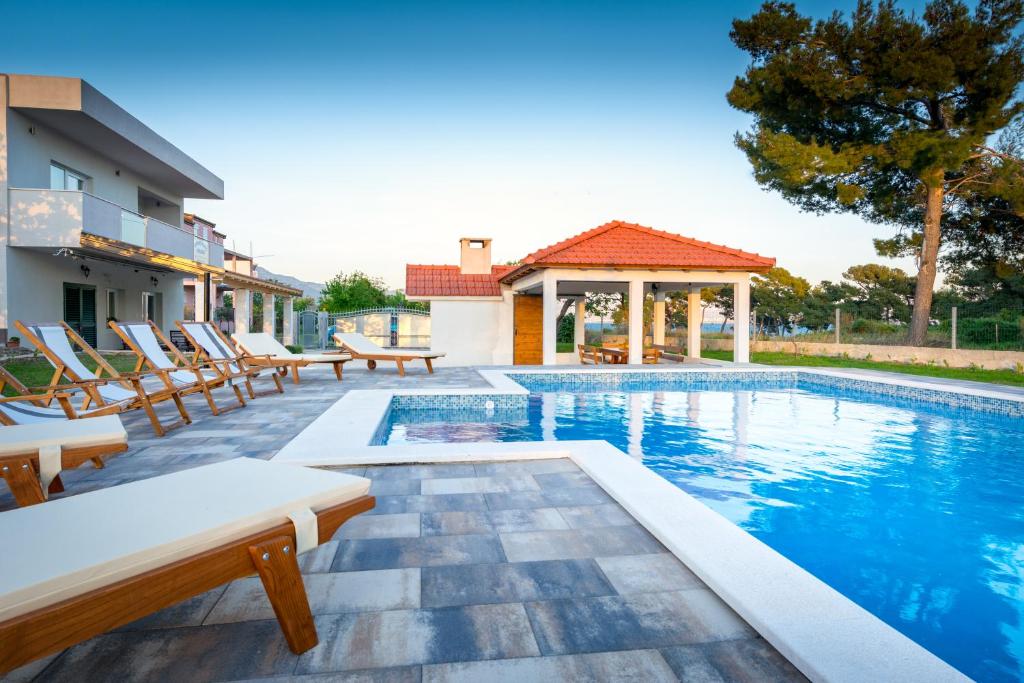 - une piscine avec des chaises et une maison dans l'établissement Villa Apartments Marko & Šimun, à Kaštela