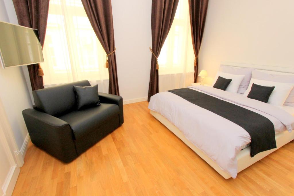 a bedroom with a bed and a black chair at Luxury apartments Krocínova in Prague