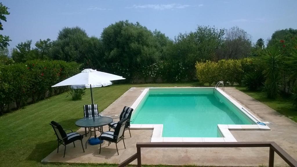 una mesa con sombrilla junto a la piscina en villa gio con piscina, en Siracusa