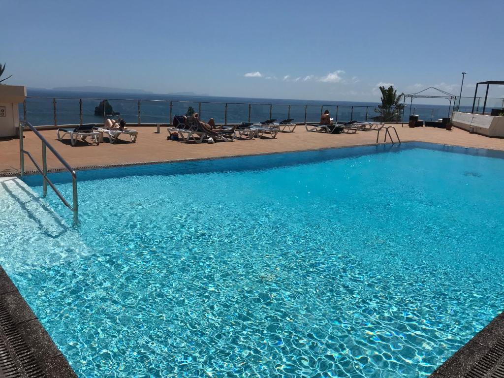 uma grande piscina azul no topo de um edifício em Apartamentos do Mar Funchal em Funchal