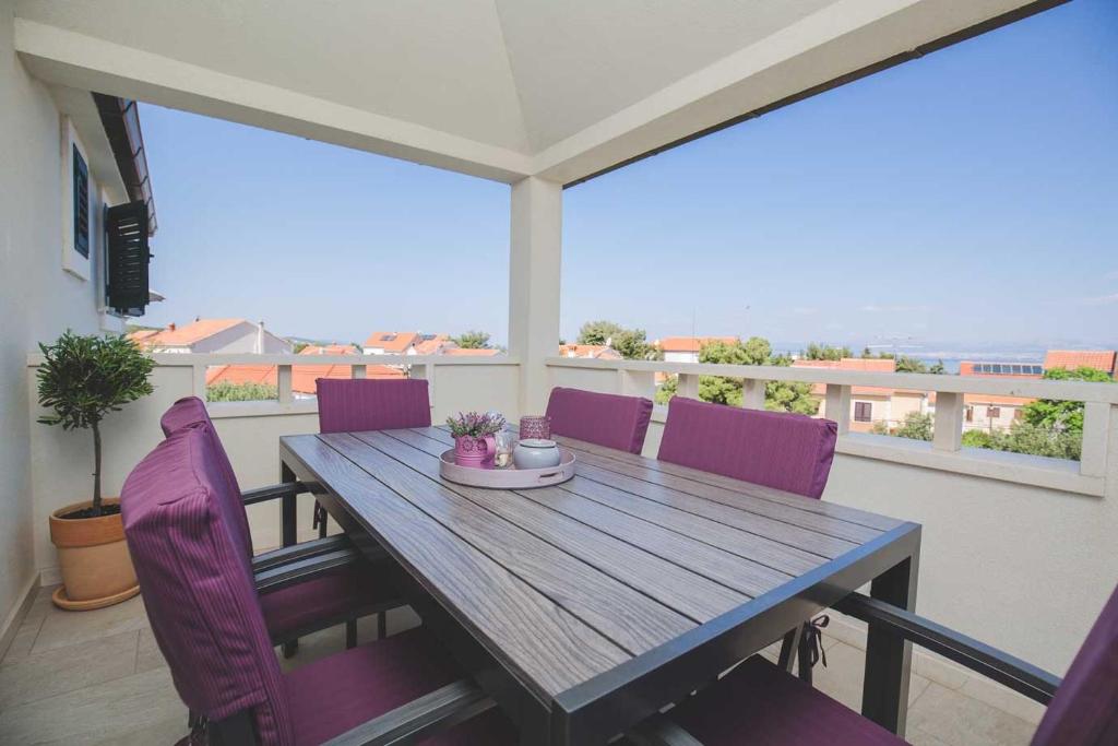 a wooden table on a balcony with purple chairs at Salsa in Supetar