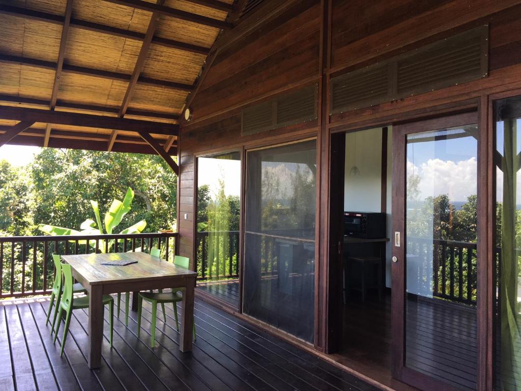 a wooden deck with a table and glass doors at Les Manguiers in Arue