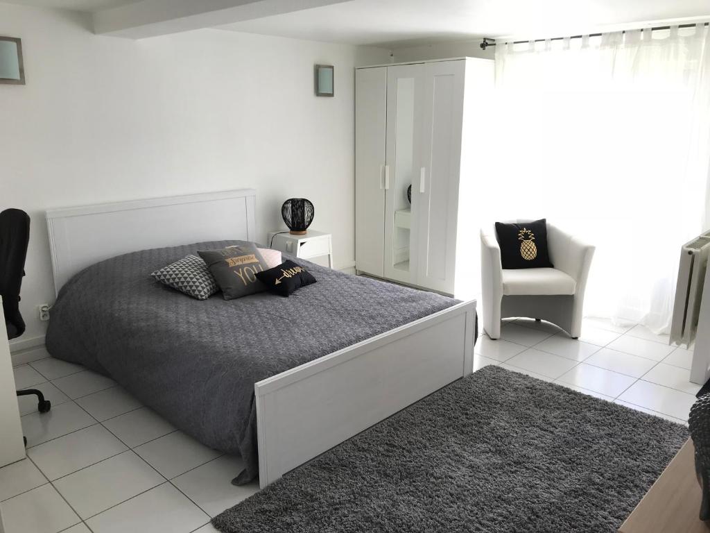 a white bedroom with a bed and a chair at Apartment 36 m² in Bretenière