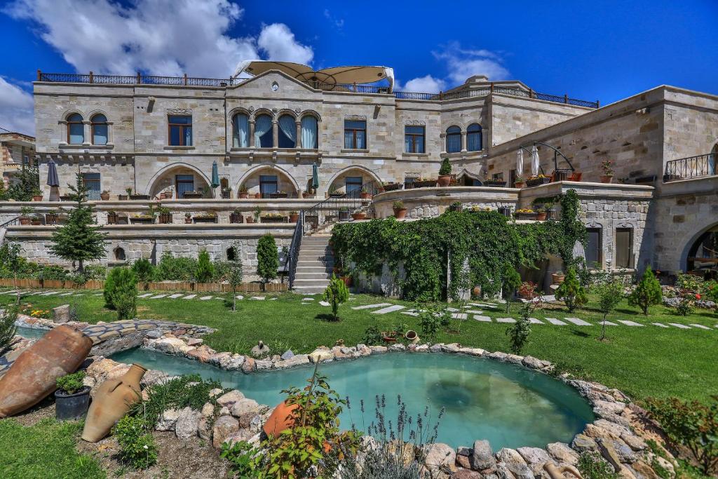 a large stone building with a pool in the yard at Goreme Inn Hotel Only Adult in Goreme