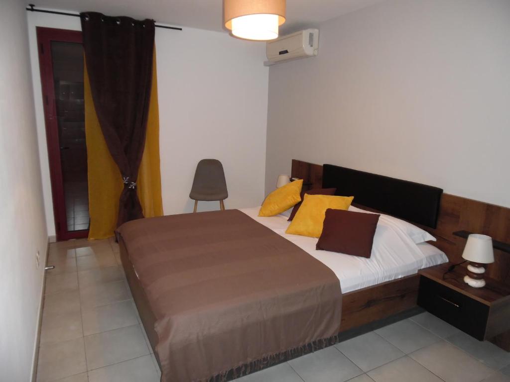 1 dormitorio con 1 cama grande con almohadas amarillas en Airport Appart, en Sainte-Clotilde