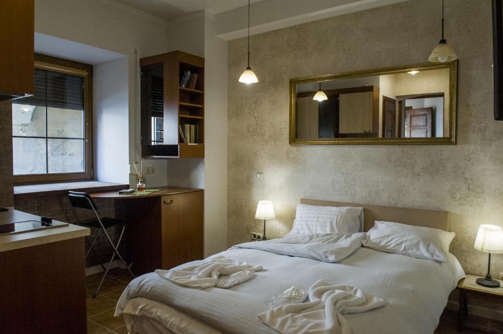 Schlafzimmer mit einem Bett mit weißer Bettwäsche und einem Spiegel in der Unterkunft Natalex Apartments in Vilnius