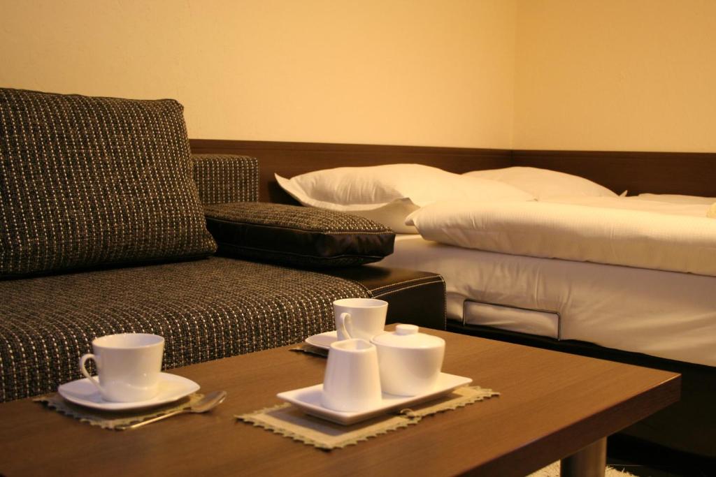 une chambre avec un canapé et une table avec des tasses et des soucoupes dans l'établissement Apartamenty Starka, à Wisła