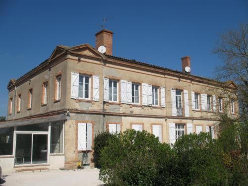 ein großes Backsteingebäude mit weißen Fenstern darüber in der Unterkunft Chateau de Faudade in Lévignac-sur-Save