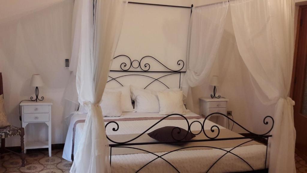 una camera con letto a baldacchino e cuscini bianchi di La Maison de Adele ad Alghero