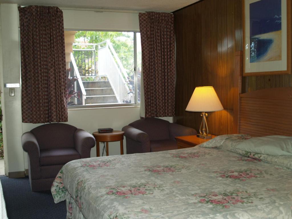a hotel room with a bed and chairs and a window at Parkview Motor Lodge in West Palm Beach