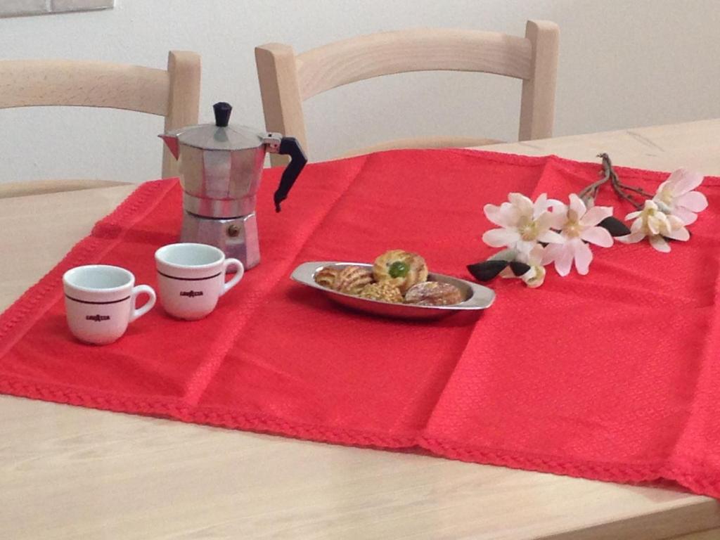 uma mesa com duas chávenas e um prato de comida num guardanapo vermelho em Casa-Lisa seminterrato em Miggiano