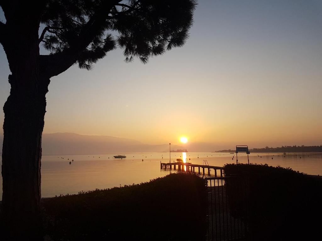 een zonsondergang boven een waterlichaam met een boom bij san felice in Manerba del Garda