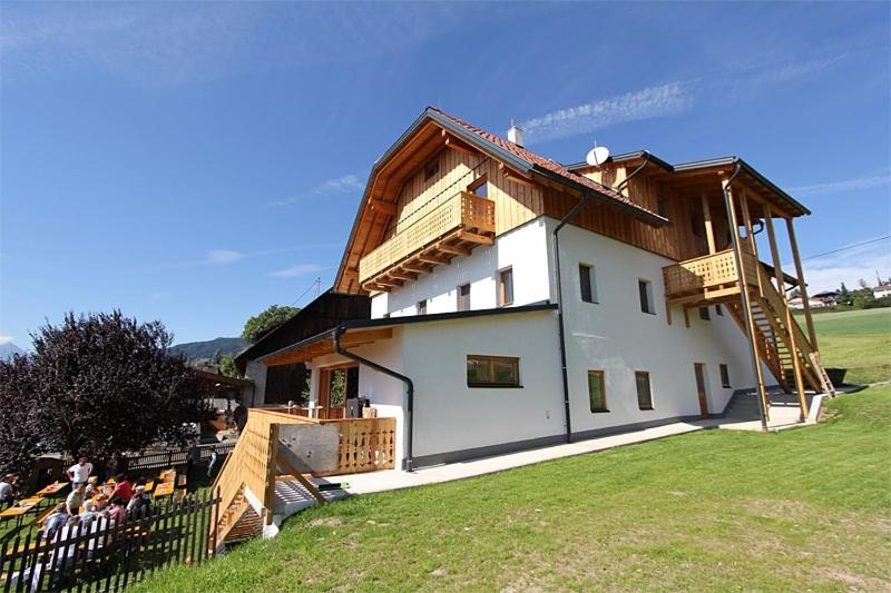 uma casa com um telhado de madeira e um grupo de pessoas em Landhaus Löscher em Seeboden