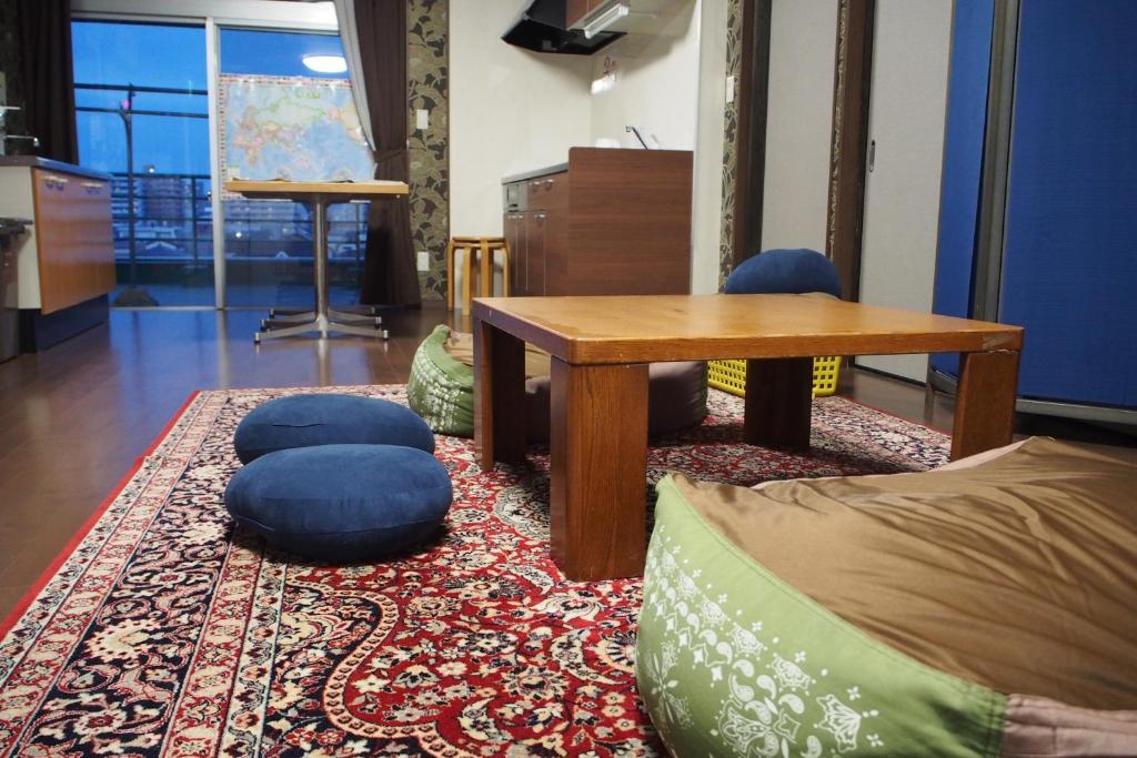 a living room with a table and chairs on a rug at Guesthouse Tiga in Kumamoto