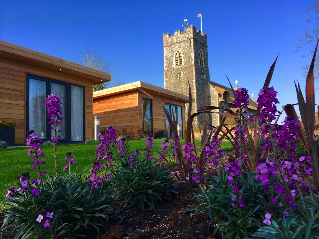 a church with a clock tower and purple flowers at The Kings Arms - Fleggburgh in Burgh Saint Margaret