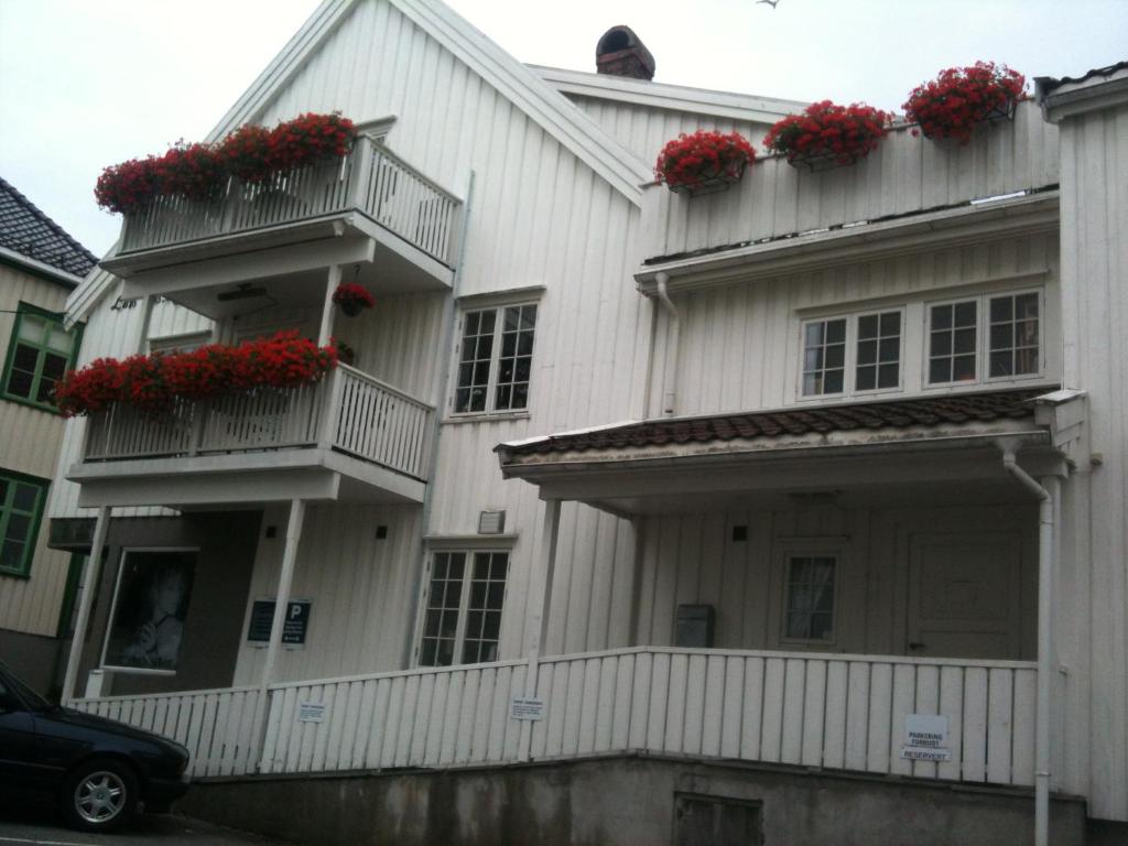 een wit huis met rode bloemen op de balkons bij Holsthuset Losji in Grimstad