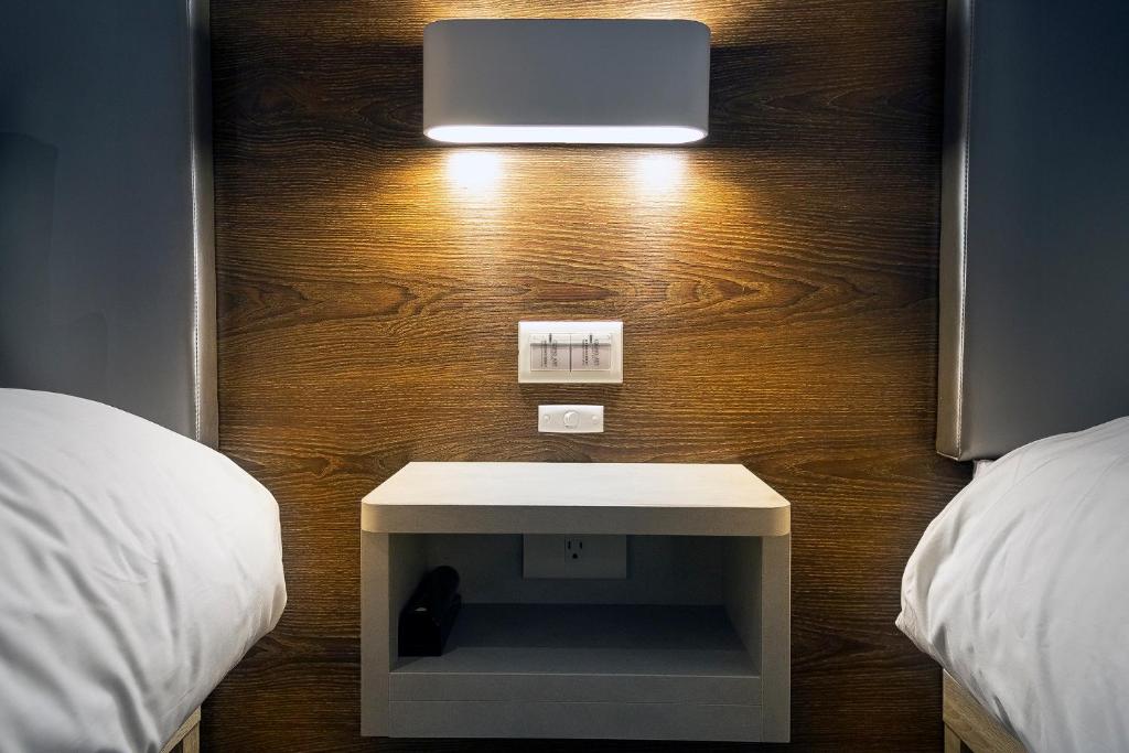 Habitación con cama con mesa blanca y pared de madera. en Greatt Hotel en Taipéi
