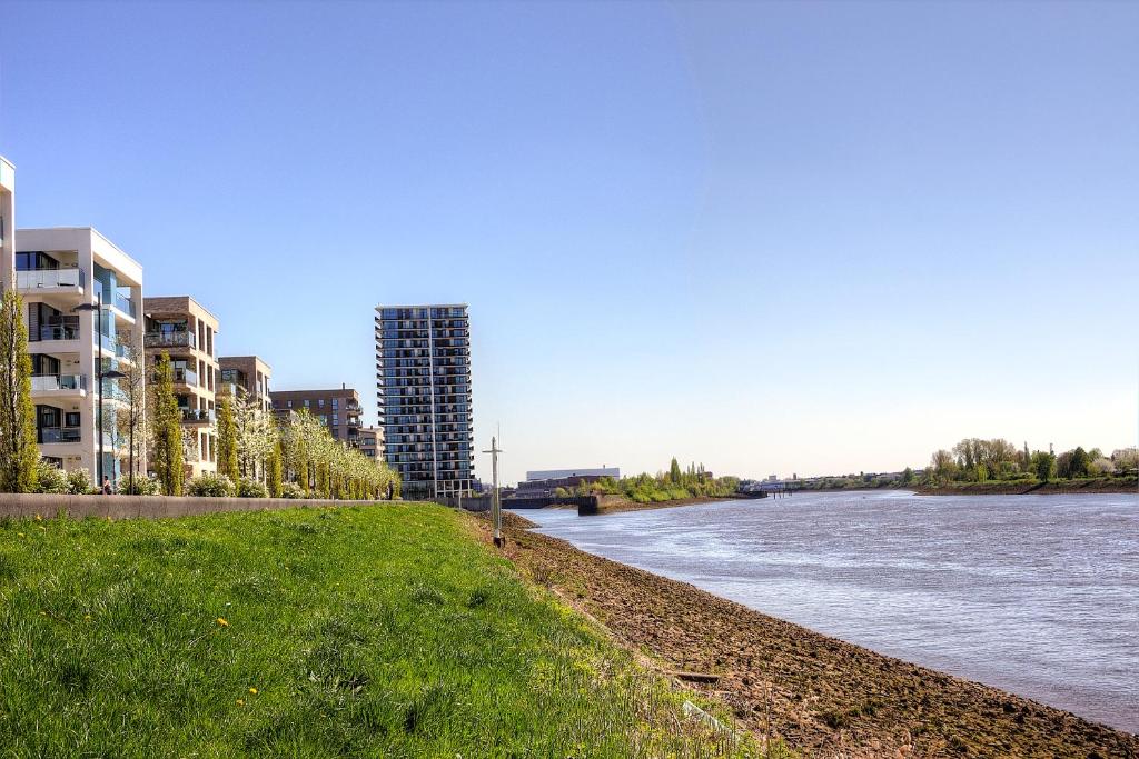 ein Fluss mit hohen Gebäuden und einem grasbewachsenen Ufer in der Unterkunft Plenus Riverloft in Bremen
