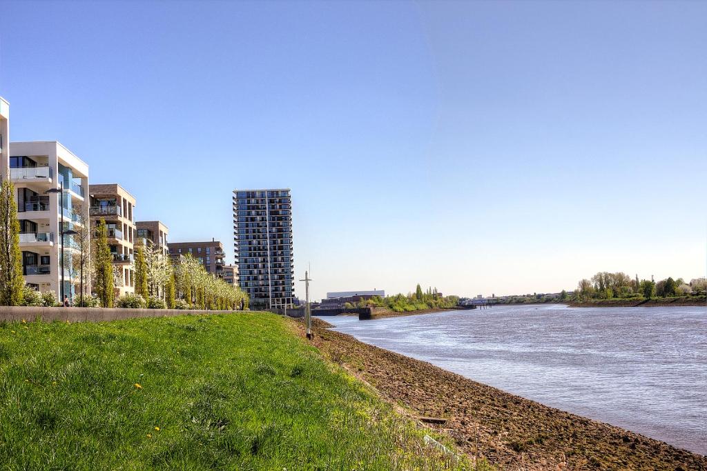 un río con edificios altos y un banco de hierba en Plenus Riverloft en Bremen