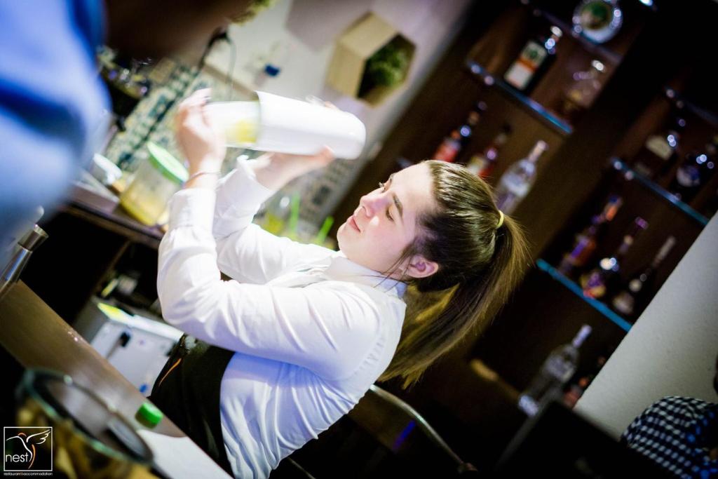 a woman holding a bottle of wine in a bar at Nest in Drobeta-Turnu Severin