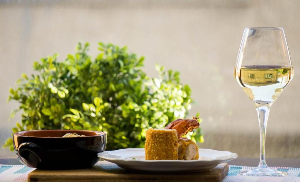 a plate of food and a glass of white wine at Nest in Drobeta-Turnu Severin