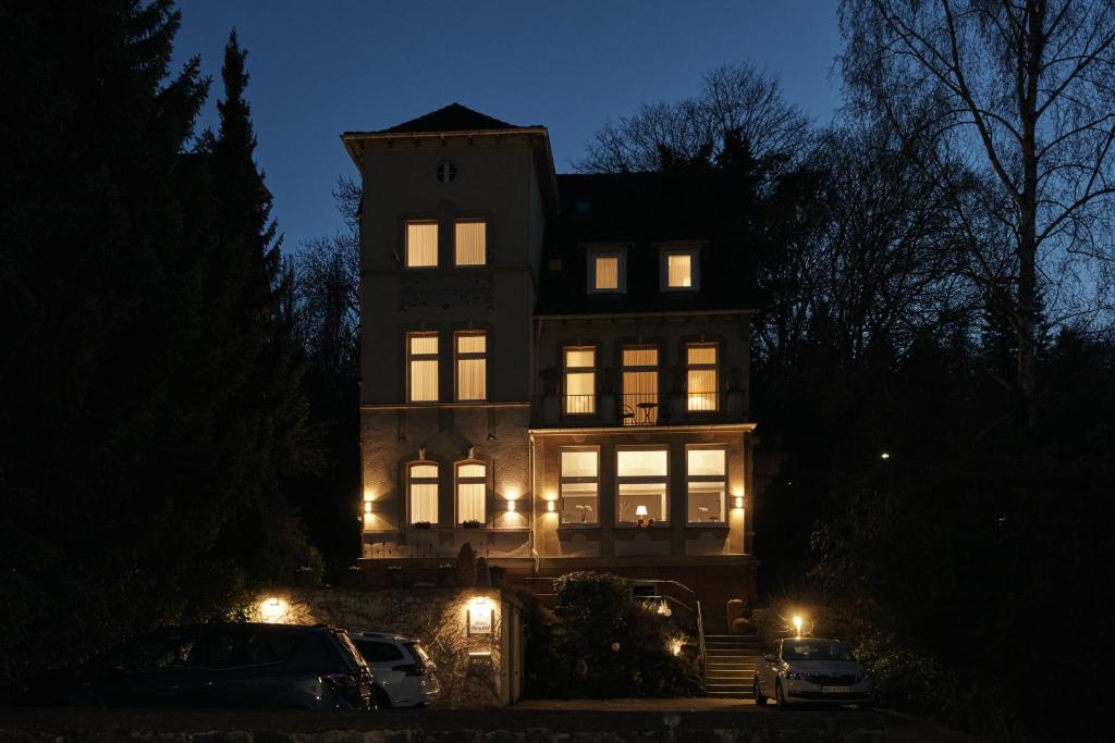 una casa grande con sus luces encendidas por la noche en Hotel Burgfeld, en Kassel