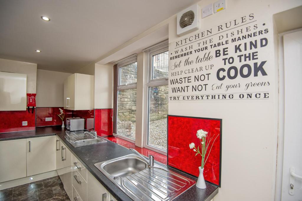 a kitchen with a sink and a red wall at Snooze Apartments in Bradford